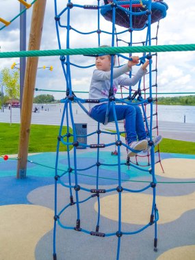 Mavi gökyüzüne karşı macera halat parkına tırmanan kız.