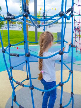 Mavi gökyüzüne karşı macera halat parkına tırmanan kız.