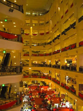 Kuala Lumpur, Malaysia - February 09, 2011: People going at 6 floors of the Suria KLCC shopping mall. The mall is located in the Kuala Lumpur City Centre district near the famous Petronas Towers. clipart