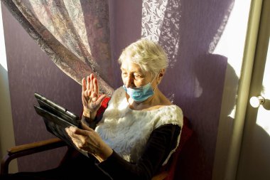 COVID-19, bağlantıda kal. Ev videosundaki mutlu yaşlı kadın dizüstü bilgisayardan ailesini arıyor ya da uzak mesafe arkadaşlarıyla internetten sohbet ediyor. Coronavirus kilitleme, Umut, bağlantılar ve teknoloji konsepti.