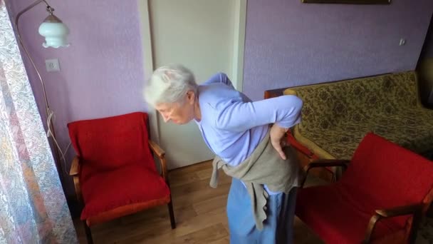 Starší žena ve věku 75 let s bolestivými pocity v bederní páteři, masírující dolní část zad ke snížení bolesti zad, trpí bolestí zad. — Stock video