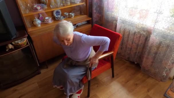 Elderly senior 75s woman with painful feelings in lumbar, massaging low back to reduce ache, suffer from backache discomfort. — Stock Video