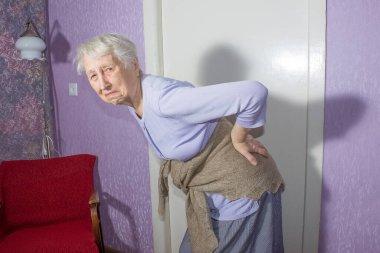 Yaşlı 75 'li yaşlarda, sırt ağrısı ve sırt ağrısını azaltmak için sırt masajı yapan yaşlı bir kadın. Yaşlıların hastalıkları, siyatik sinir hasarı konsepti