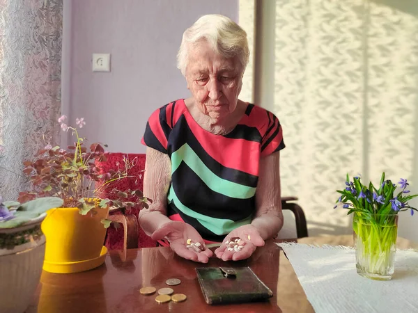 Senior woman sitting at home with pills. Poverty concept. All money was spent for pill