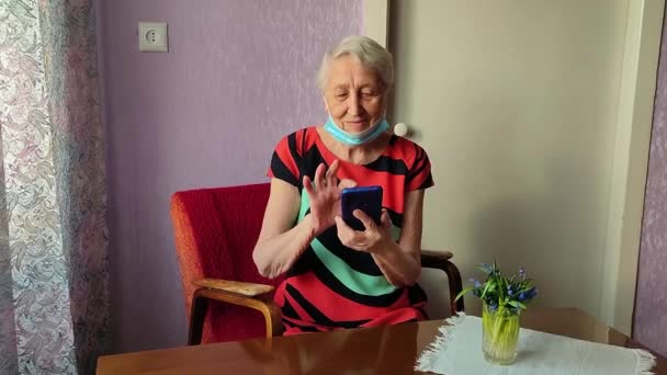 De Covid-19, gezondheid, veiligheid en pandemie concept - senior oude eenzame vrouw zit met telefoon — Stockvideo