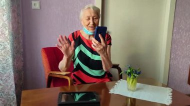 Covid-19, sağlık, güvenlik ve salgın konsepti - telefonda oturan yaşlı ve yaşlı kadın