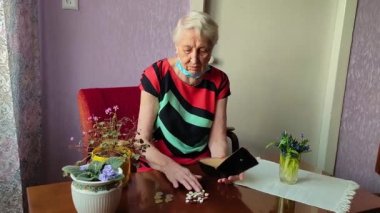 Son sınıf öğrencisi kadın elinde haplarla pencere eşiğinde oturuyor.