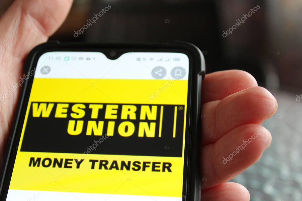 Kyiv, Ukraine - April 18, 2021: Female hand holding smartphone after unboxing and testing by installing the app application software Western Union money transfer app