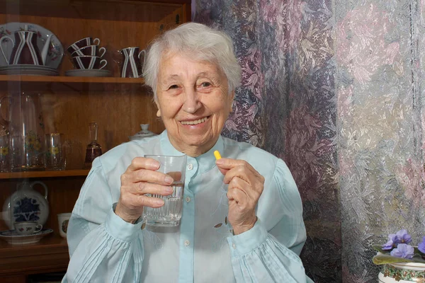 Старшая Седовласая Женщина Принимает Таблетки Держа Стакан Воды Дома — стоковое фото
