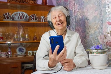 Evde şarkı söyleyen, kulaklıklı, olgun yaşlı bir kadın. Pozitif ve mutlu duygular kavramı