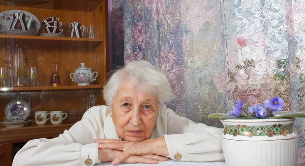 Elderly lonely woman depressed sitting at the table at home