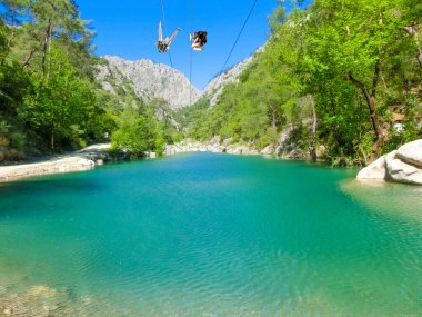 Türkiye 'nin Goynuk ve Antalya kenti yakınlarındaki Harmony kanyonunda halatla kayan bir turist. macera konsepti