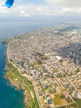 İniş sırasında Antalya 'nın hava görüntüsü. Akdeniz 'in mavi suları, güzel körfez, bir sürü küçük renkli ev ve sabah güneşiyle aydınlanan kumlu kumlu plaj.