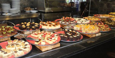 Açık büfedeki raflarda bulunan yiyecekler, Türkiye 'de soyut otel veya Kemer' deki tatil beldesindeki her şeyi kapsıyor. Tatlı kekler ve tatlı