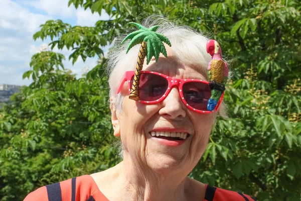 Funny senior woman in sunglasses against summer background