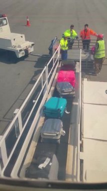 Antalya, Türkiye - 15 Mayıs 2021: havaalanı çalışanları uçak bagajlarından çanta, bavul ve yolcu bagajlarını boşaltıyor. Aydınlatıcıdan görüntü, uçak penceresi.