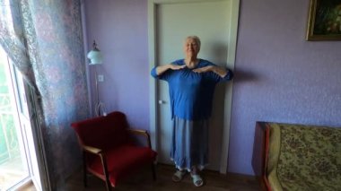 Evdeki oturma odasında jimnastik yaparken son sınıf öğrencisi bir kadın..