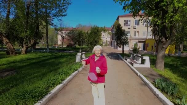 Mujer mayor en el prado jugando bádminton en el parque. — Vídeos de Stock