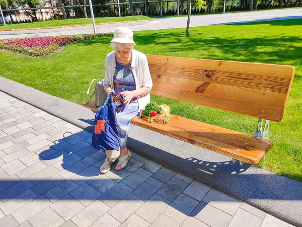 Female hands holding empty purse after shopping at park. Senior woman shows her empty wallet. Bankruptcy. The concept of poverty.