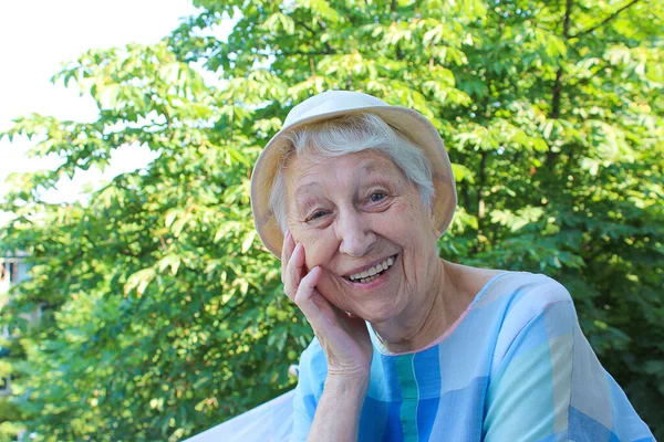 一位积极的老年妇女在阳台上的树上微笑着 — 图库照片