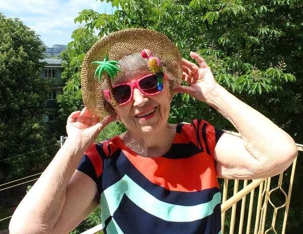 Funny senior woman in sunglasses against summer background