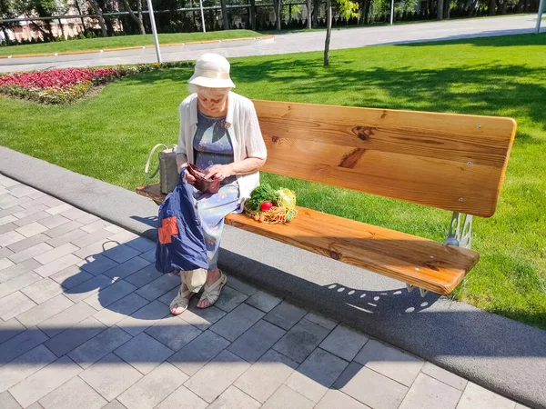 Female hands holding empty purse after shopping at park. Senior woman shows her empty wallet. Bankruptcy. The concept of poverty.