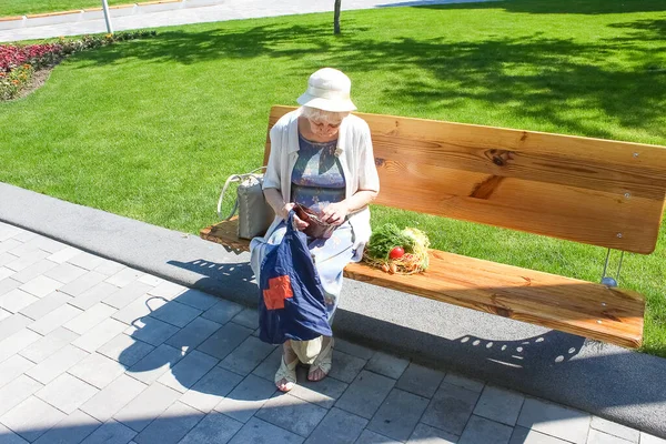 Female hands holding empty purse after shopping at park. Senior woman shows her empty wallet. Bankruptcy. The concept of poverty.