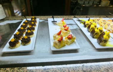 Açık büfedeki raflarda bulunan yiyecekler, Türkiye 'de soyut otel veya Kemer' deki tatil beldesindeki her şeyi kapsıyor. Tatlı kekler ve tatlı