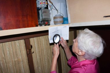 Korkmuş yaşlı kadın elektrik sayacını kontrol ediyor - tüketim ve pahalı elektrik kavramı