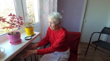 Gaz faturasını kaloriferin önünde tutan yaşlı kadın. Kışın ısıtma için ödeme.