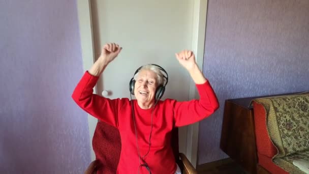 快乐的笑着笑着笑着 戴着耳机 拿着手机在家里跳舞的老妇人 — 图库视频影像