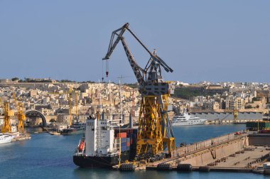 Valletta, Malta - Kargo vinçleri ve büyük Atlantik gümüşü limandaki tahkimatlar ve teknelerin yakınına yanaştı.