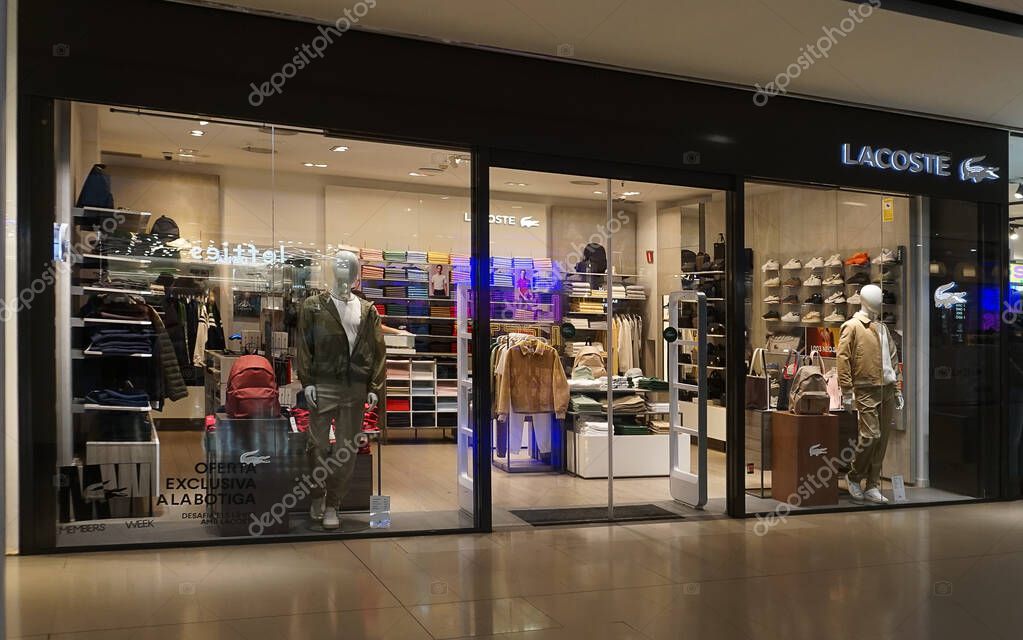 Barcelona, Spain - September 26, 2025: the exterior of a Lacoste store features a large sale sign. The glass facade displays a stylish design with merchandise visible inside the shop.