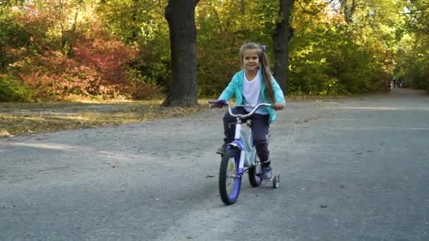 Klein meisje paardrijden vier wielen fiets in park — Stockvideo