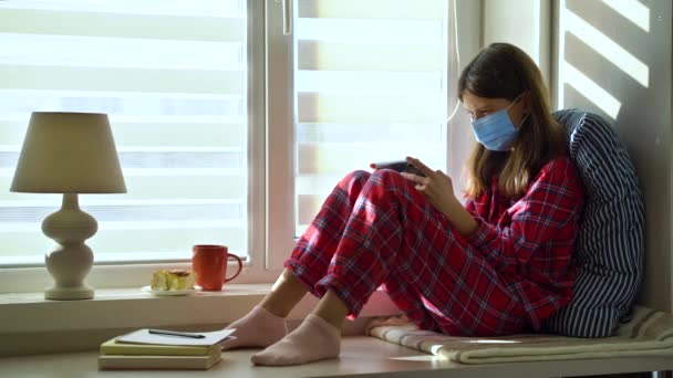 Κορίτσι με μάσκα κάθεται στο σπίτι και παίζει online παιχνίδι — Αρχείο Βίντεο