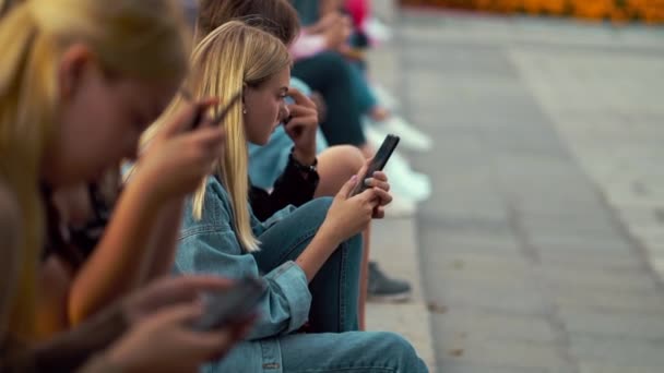 Grupp tonåringar som sitter på gatan och använder smartphones — Stockvideo