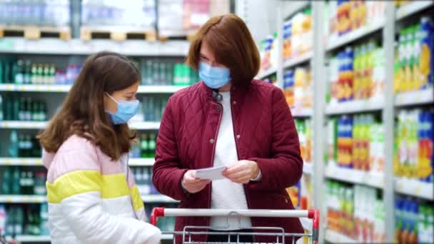 Mutter und Tochter in Masken beim Einkaufen im Supermarkt — Stockvideo