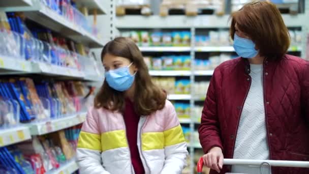 Madre e hija en máscaras comprando chocolate en la tienda — Vídeos de Stock