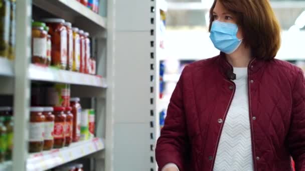 Жінка в масці купує мариновані помідори в супермаркеті — стокове відео