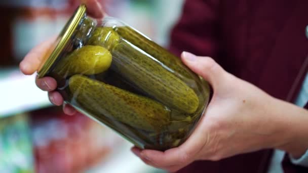 Manos femeninas sosteniendo frasco de pepinos en escabeche en el supermercado — Vídeo de stock