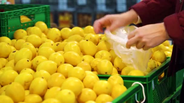 Ženské ruce sbírat citróny a dávat do plastového sáčku v obchodě — Stock video