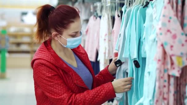 Femme achetant des vêtements de bébé dans un grand magasin pendant une pandémie — Video