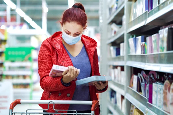 Woman choosing chocolates in supermarket during pandemic
