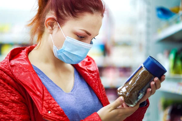 Tıp maskeli kadın süpermarkette hazır kahve seçiyor.