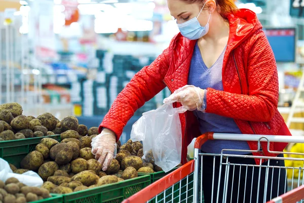 Wanita memetik kentang di supermarket selama pandemi Stok Foto