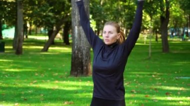 Zıplayan ve parkta egzersiz yapan zinde bir kadın.