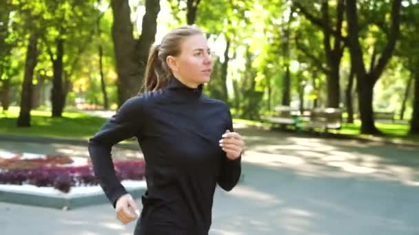 Fitte Frau joggt bei sonnigem Wetter im Park — Stockvideo