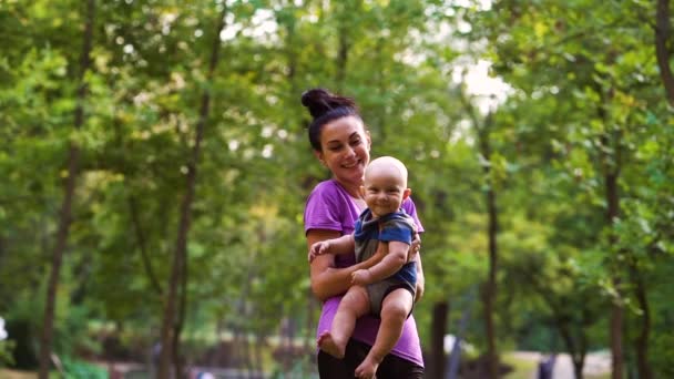 Mère soulevant bébé dans l'air dans le parc — Video