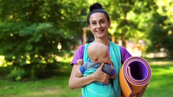 Apto mãe carregando bebê em funda para aula de ioga — Vídeo de Stock