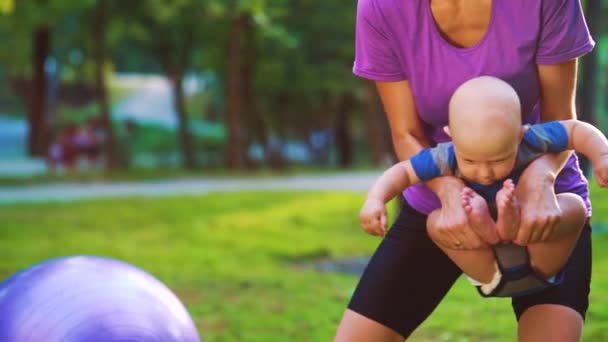 Mama robi gimnastykę z dzieckiem w parku — Wideo stockowe